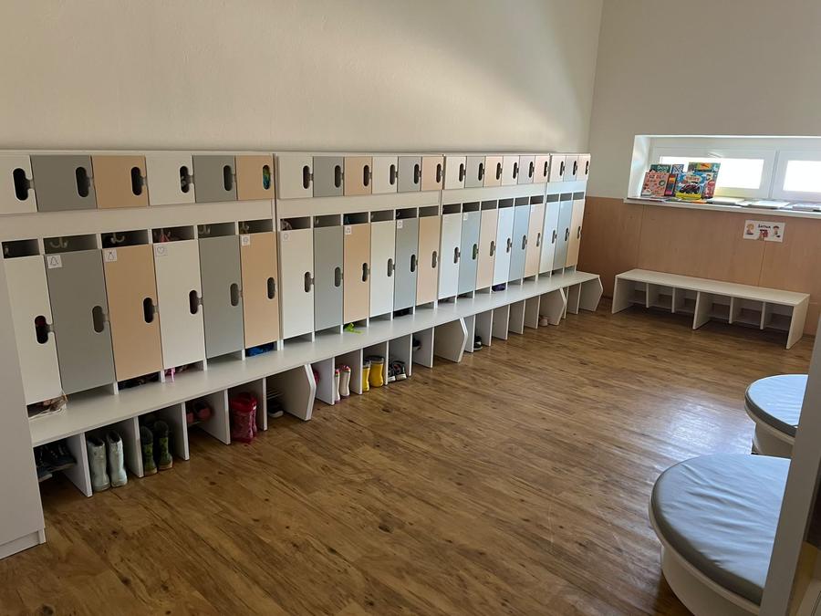 Šatna s barevnými skříňkami, lavicemi a policemi na boty